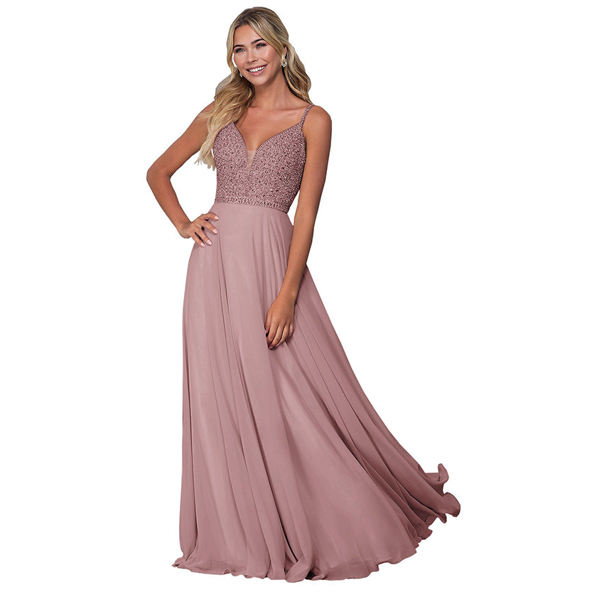 Smiling woman in a flowing, sleeveless dusty pink gown with beaded bodice and V-neckline, exuding elegance and grace against a white background.