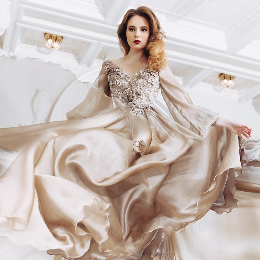 Women modelling beautiful cream satin flowing ball gown evening dress.