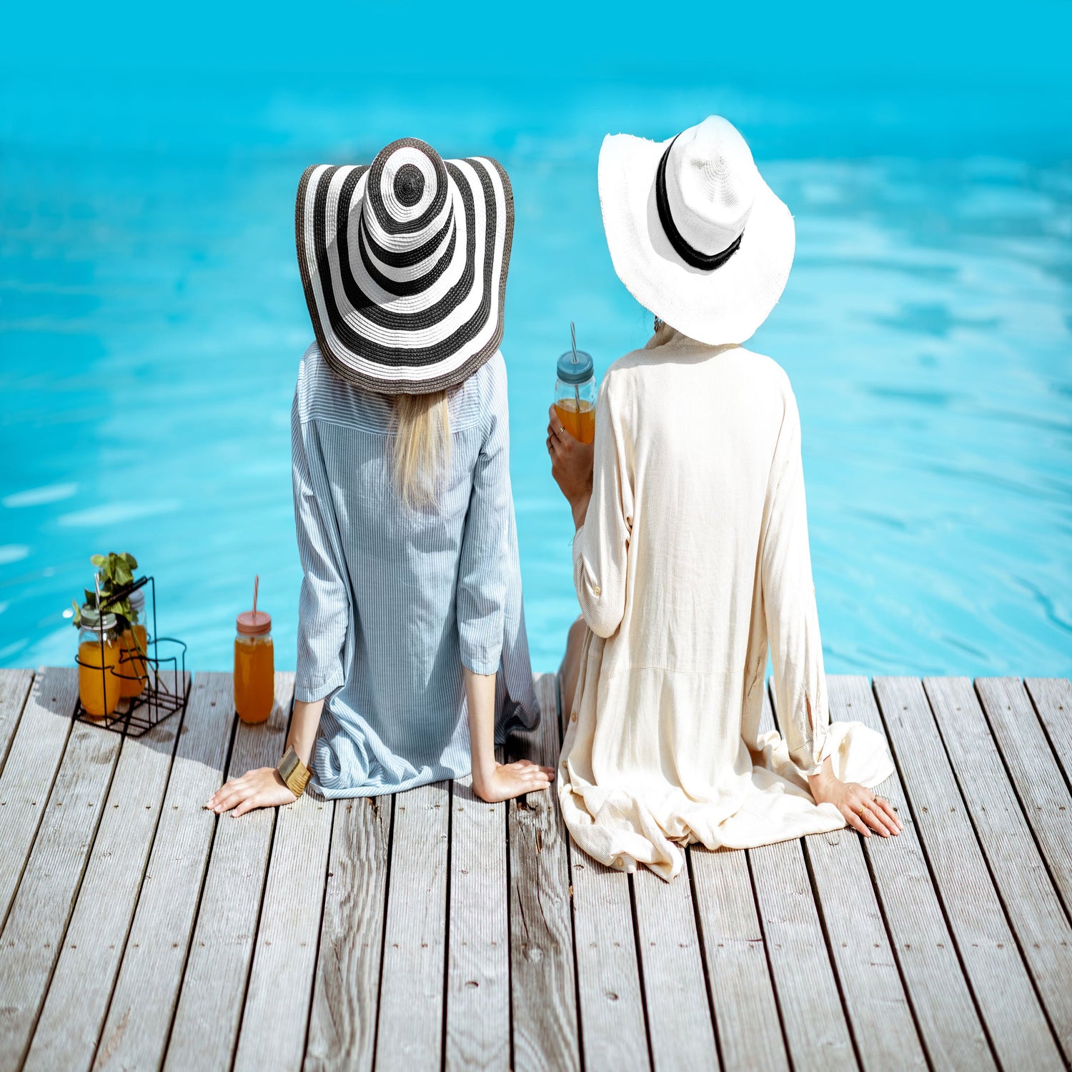Two women sitting poolside modelling shirts.