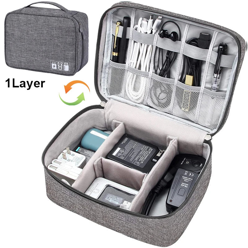 A gray tech organizer case with multiple compartments for cables, chargers, and electronic devices, fully unzipped for visibility.