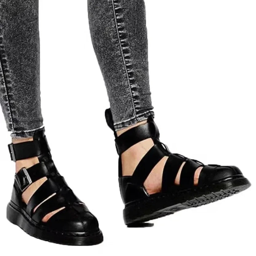 Person wearing black strappy sandals and faded black jeans.