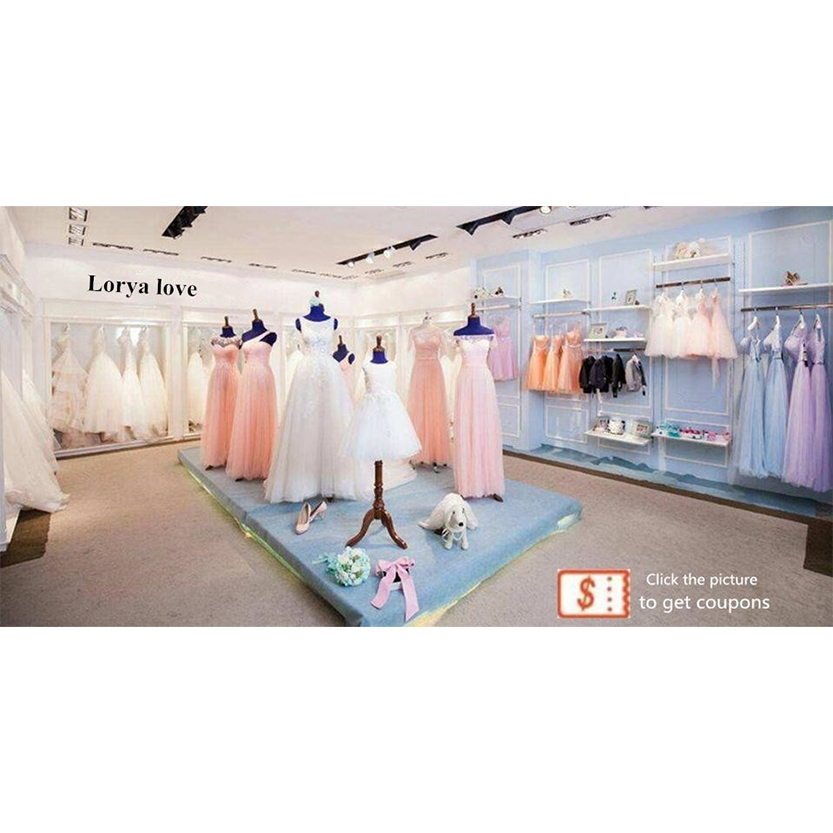 Bridal shop display featuring pastel pink and white dresses on mannequins. Light blue walls with more dresses on racks. Elegant, serene atmosphere.