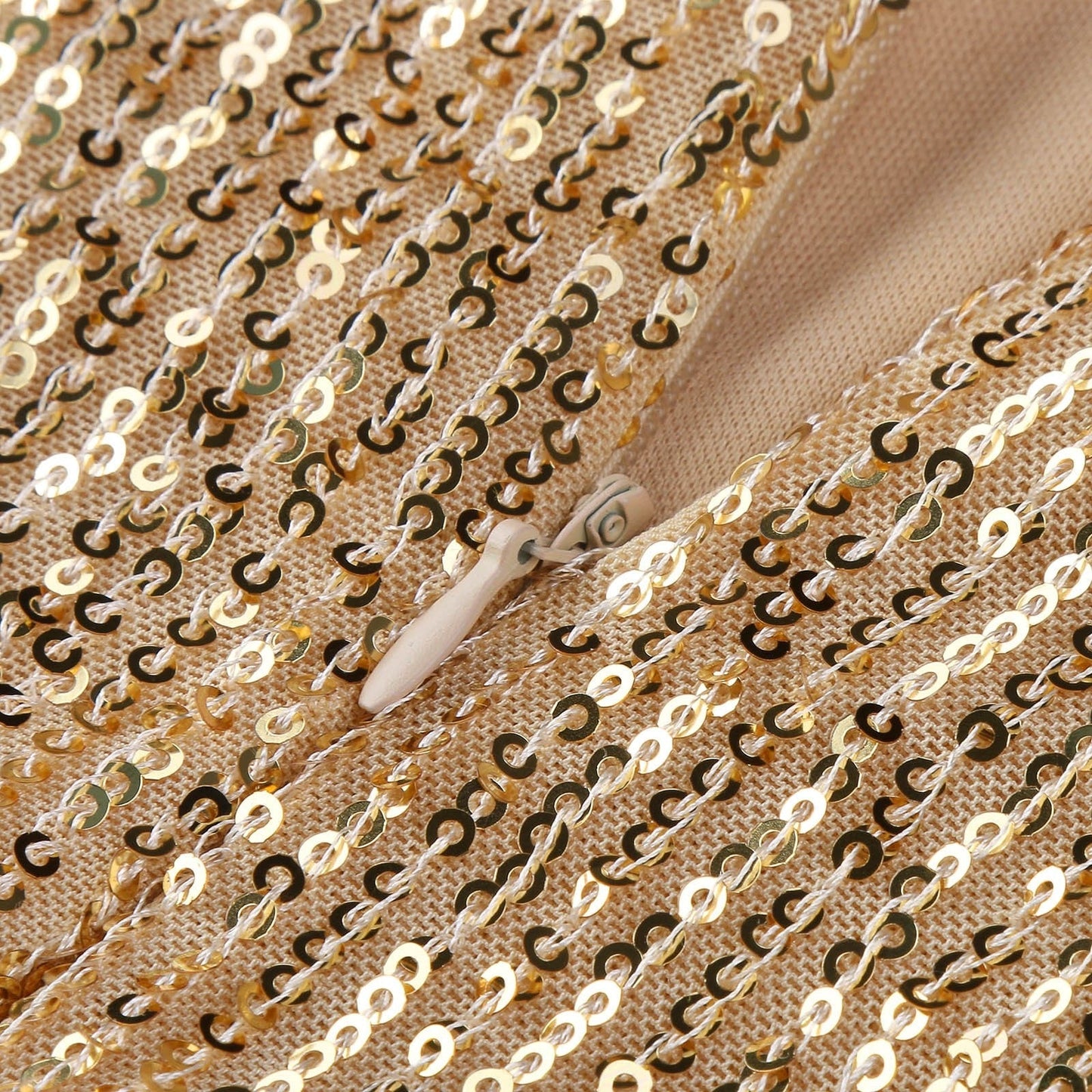 Close-up of a beige knit fabric with shimmering gold sequins in neat rows. A small wooden crochet hook is entangled, suggesting craftwork.