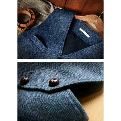 Close-up of a blue herringbone vest with a pocket, showcasing dark buttons, paired with leather straps and a wooden hanger in background.