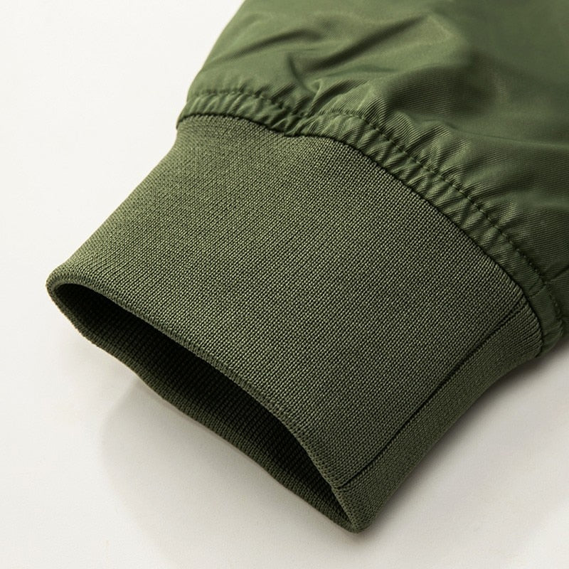 Close-up of a green jacket sleeve, featuring a ribbed cuff made of stretchy material. The fabric has a smooth texture, conveying a casual, cozy feel.