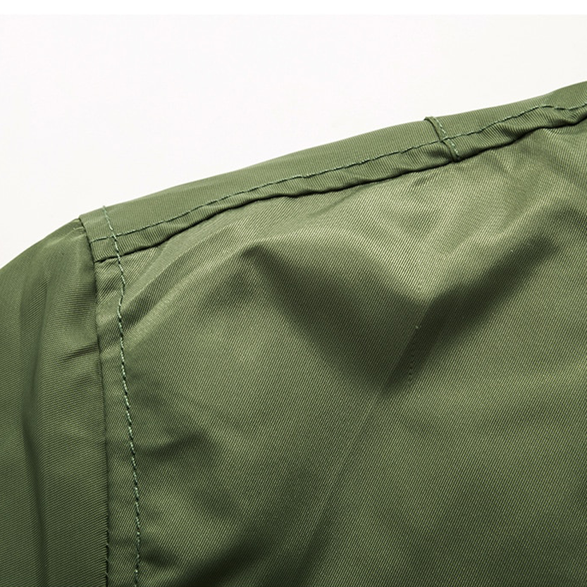 Close-up of an olive green fabric with visible stitching, possibly part of a garment. The texture is smooth, conveying a simple and functional design.