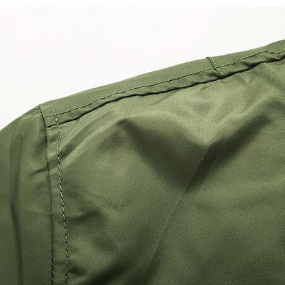 Close-up of an olive green fabric with visible stitching, possibly part of a garment. The texture is smooth, conveying a simple and functional design.