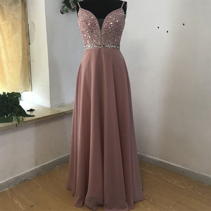 Elegant mauve evening gown with a sequined bodice and thin straps, displayed on a mannequin against a simple indoor setting, conveying sophistication.