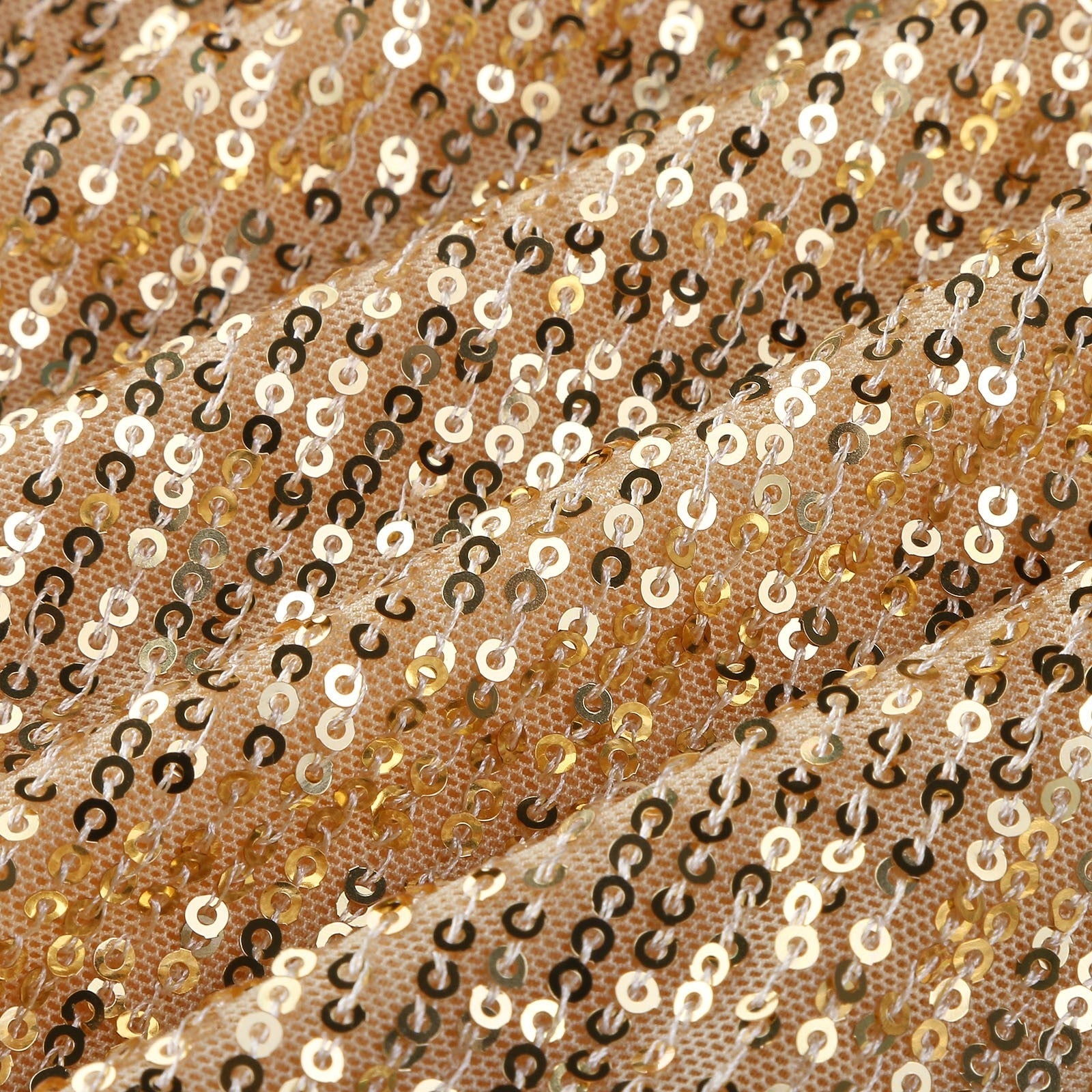 Gold sequins densely cover a textured fabric, creating a shimmering effect. The surface undulates, reflecting light for a glamorous vibe.