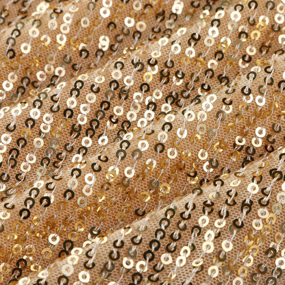 Gold sequins densely cover a textured fabric, creating a shimmering effect. The surface undulates, reflecting light for a glamorous vibe.