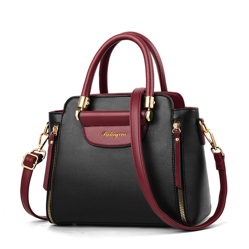 Stylish black handbag with burgundy accents, gold hardware, and dual handles; features a removable shoulder strap for versatility.
