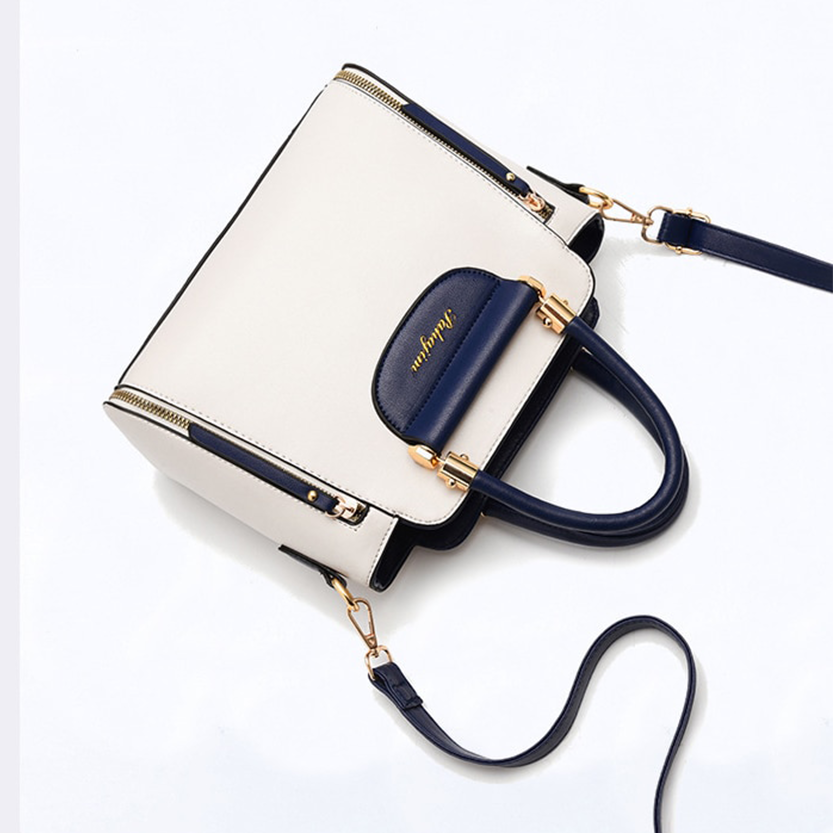 Stylish cream and navy handbag with gold accents, featuring dual handles and a detachable shoulder strap.