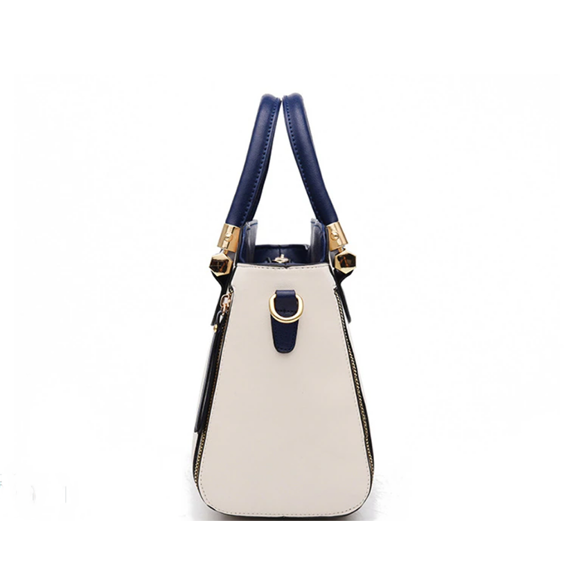 Stylish handbag featuring a cream body, navy accents, and gold hardware, with dual handles for easy carrying.