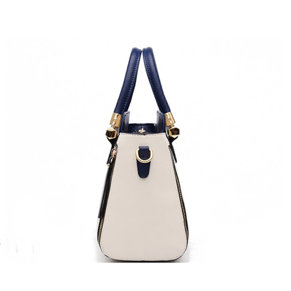 Stylish handbag featuring a cream body, navy accents, and gold hardware, with dual handles for easy carrying.