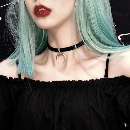 A woman with light blue hair wears a black off-the-shoulder top, red lipstick, and a black choker necklace featuring a silver crescent moon pendant.