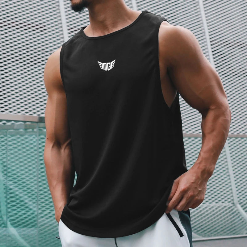 A muscular man in a black tank top stands confidently, showcasing his toned arms against a modern architectural backdrop.