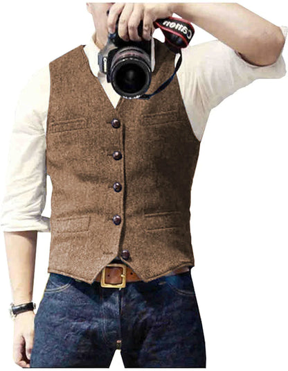 A man wearing a brown vest over a white shirt, holding a camera up as if taking a photo. He has blue jeans and a belt.