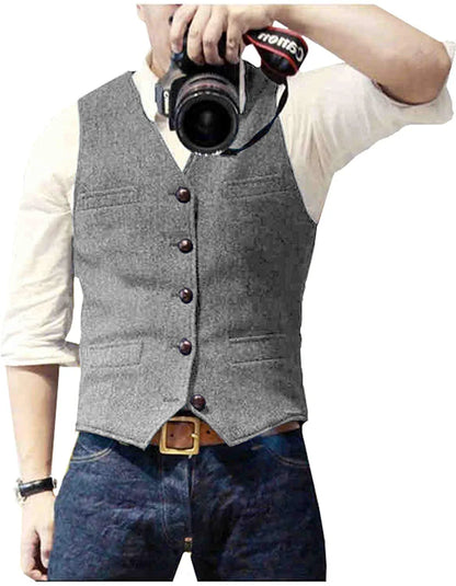 A man in a gray vest takes a selfie with a DSLR camera, wearing a white shirt and dark jeans, showcasing a stylish, casual look.