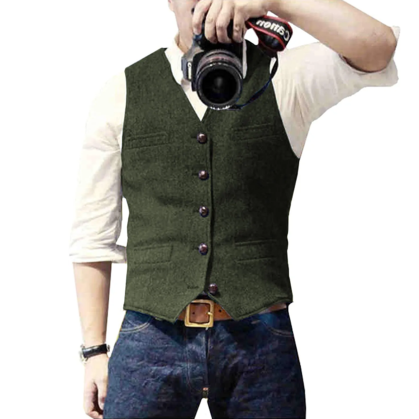 A man wearing a green vest and a white shirt poses while holding a camera, ready to take a photograph.
