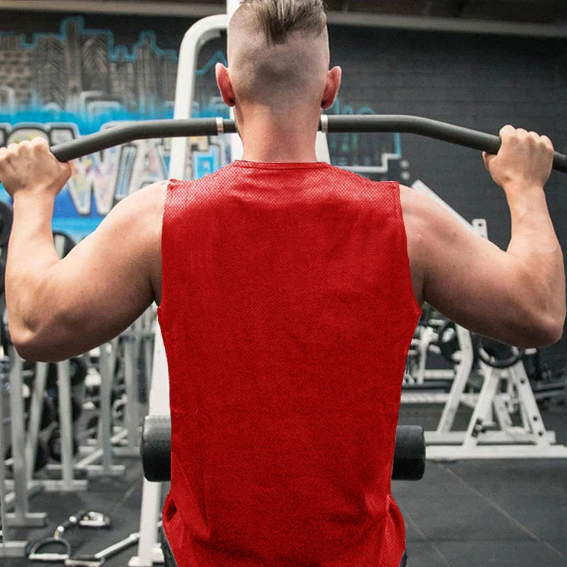 A muscular man in a red sleeveless shirt performs a pull-up in a gym, showcasing his strong back and arms.