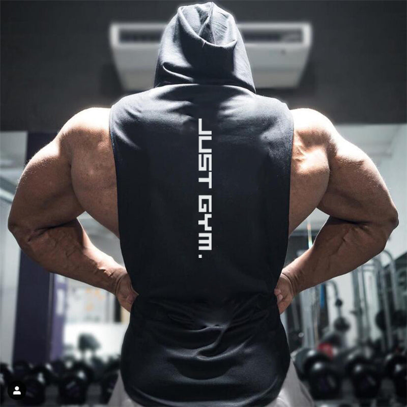 A muscular individual in a sleeveless hoodie stands with their back to the camera, showcasing broad shoulders, with "JUST GYM." printed vertically.