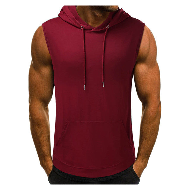 Muscular person wearing a sleeveless maroon hoodie with drawstrings, hands in pockets, against a white background. The tone is casual and sporty.