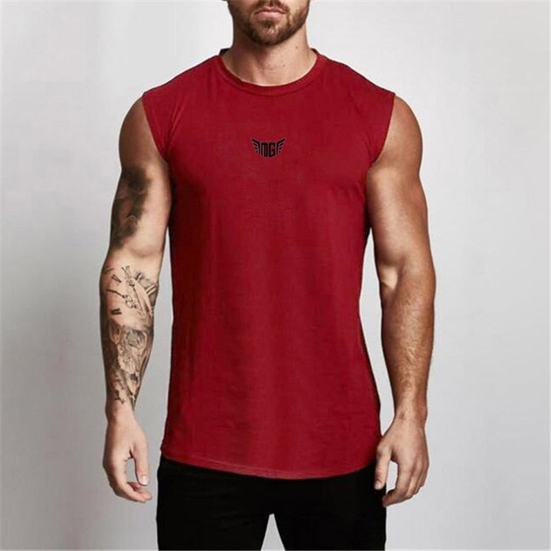 A muscular man wearing a sleeveless red shirt with a small black logo on the chest, showcasing his tattoos and fit physique.