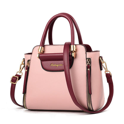 Stylish two-tone handbag with a soft pink body and burgundy accents, featuring gold hardware and a removable strap for versatility.