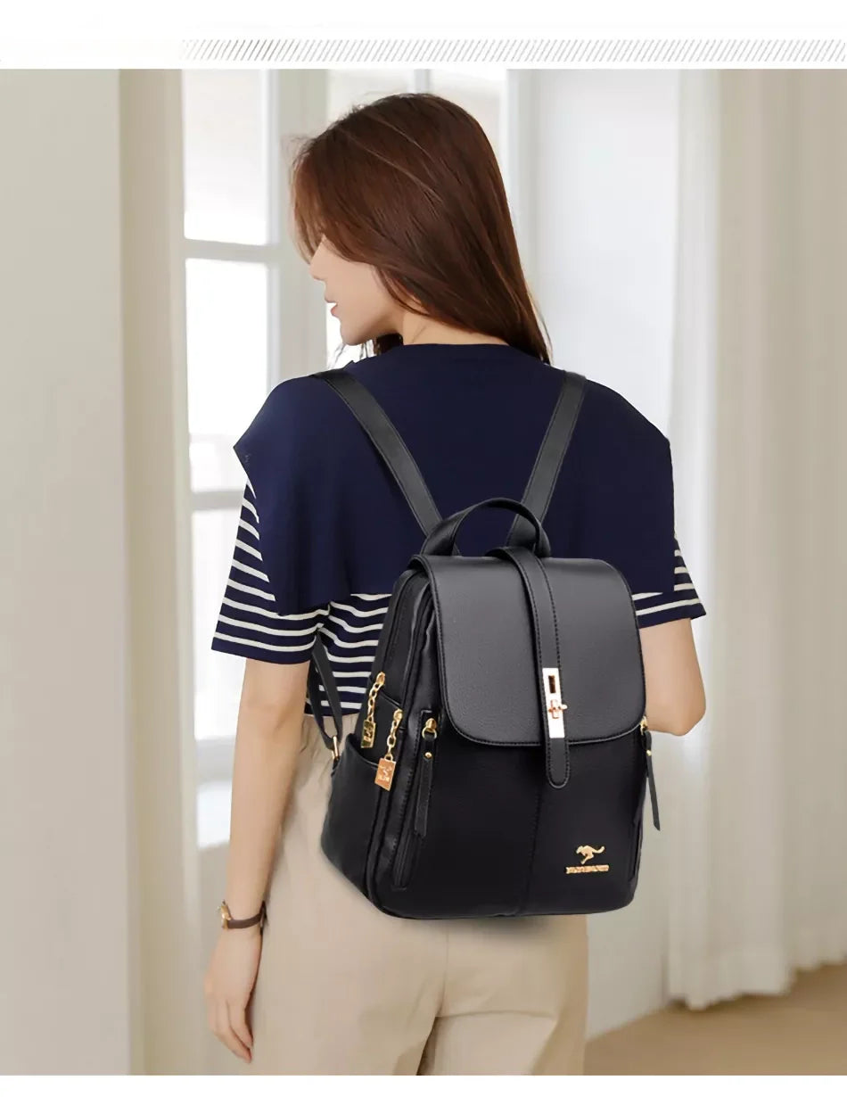 A woman with long hair wears a navy and white striped shirt, showcasing a stylish black backpack with gold accents.