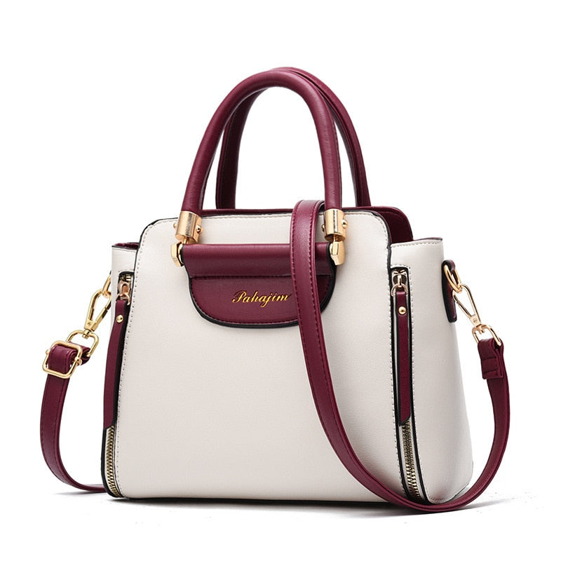 A stylish two-tone white and burgundy handbag with gold accents and a detachable shoulder strap. Elegant and modern design.