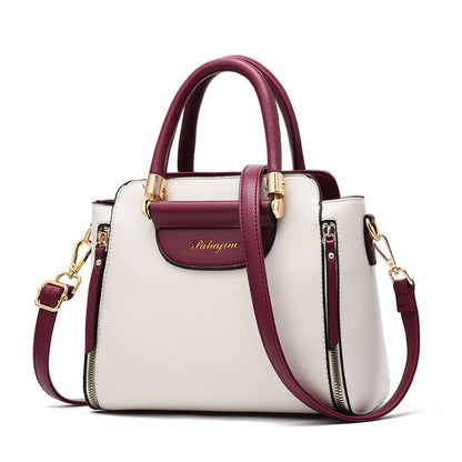 A stylish two-tone white and burgundy handbag with gold accents and a detachable shoulder strap. Elegant and modern design.