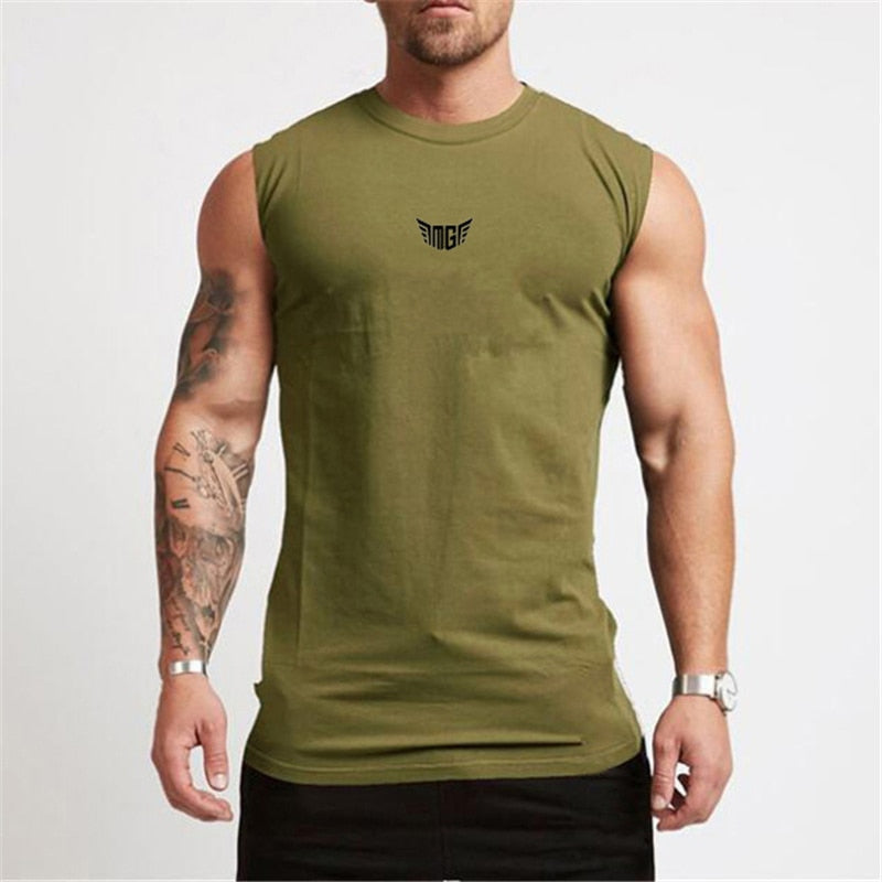 A muscular man in an olive green sleeveless shirt with a small black logo, showcasing his tattoos and wearing a watch.