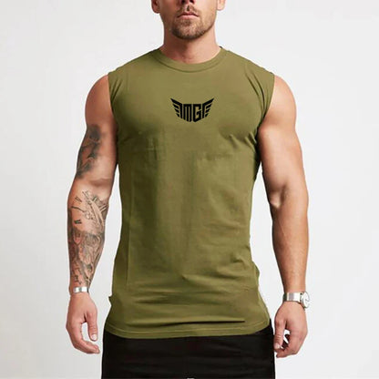 A muscular man in an olive green sleeveless shirt with a black logo on the chest, showcasing his tattoos and a silver watch.