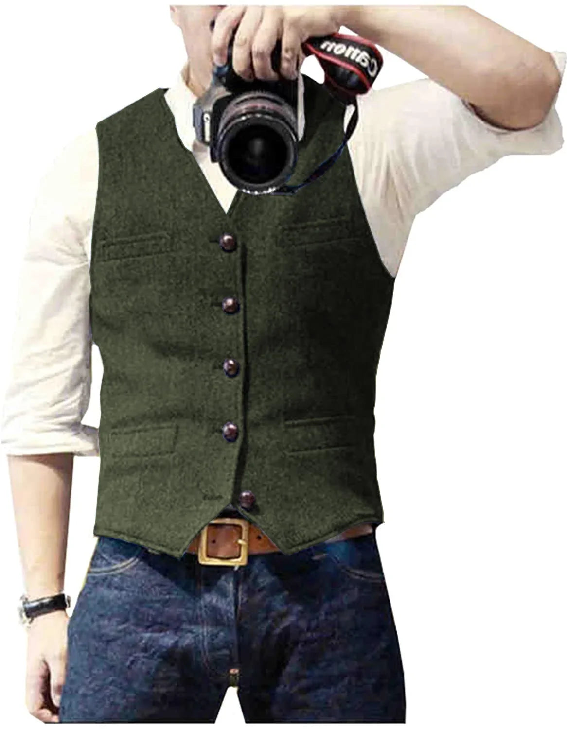 A man in an olive green vest poses for a photo, holding a camera with a Canon strap, wearing blue jeans and a white shirt.