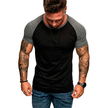 Man wearing a black and gray t-shirt with tattoos on arms against a white background