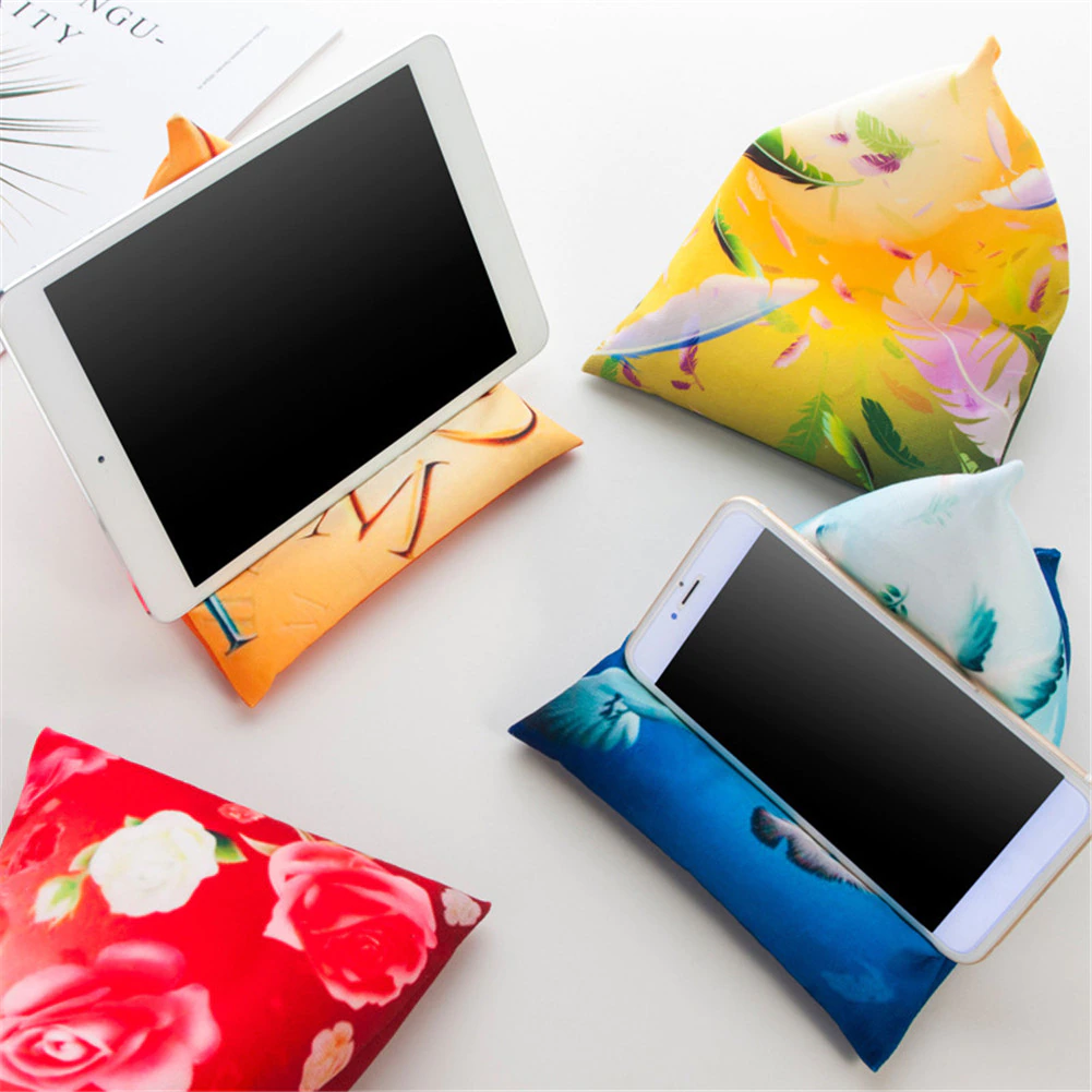 A smartphone resting on a colorful fabric phone stand shaped like a pyramid, designed for hands-free viewing.