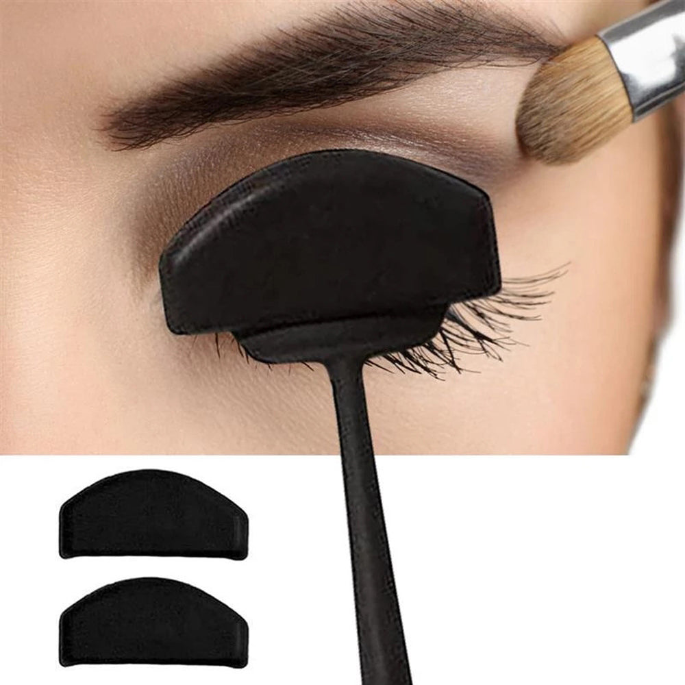 pClose-up of an eye with a black eyeshadow shield ositioned above the lashes. A brush applies shadow to the eyelid. Two extra shields are pictured below.
