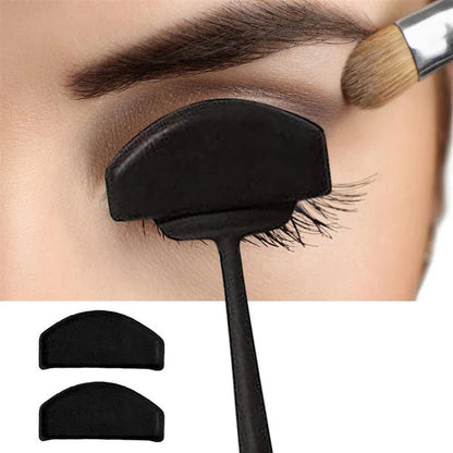 pClose-up of an eye with a black eyeshadow shield ositioned above the lashes. A brush applies shadow to the eyelid. Two extra shields are pictured below.