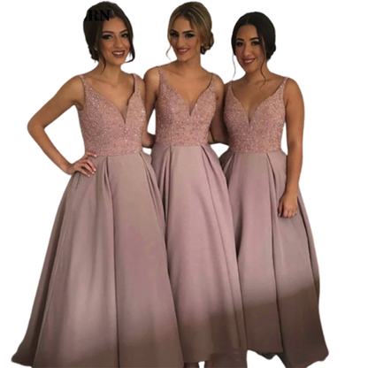 Three women stand side by side, smiling, in matching floor-length mauve dresses with sparkling bodices and pleated skirts, conveying elegance and joy.