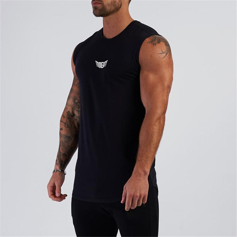 A muscular man wearing a sleeveless black workout shirt with a white logo stands against a light gray background.
