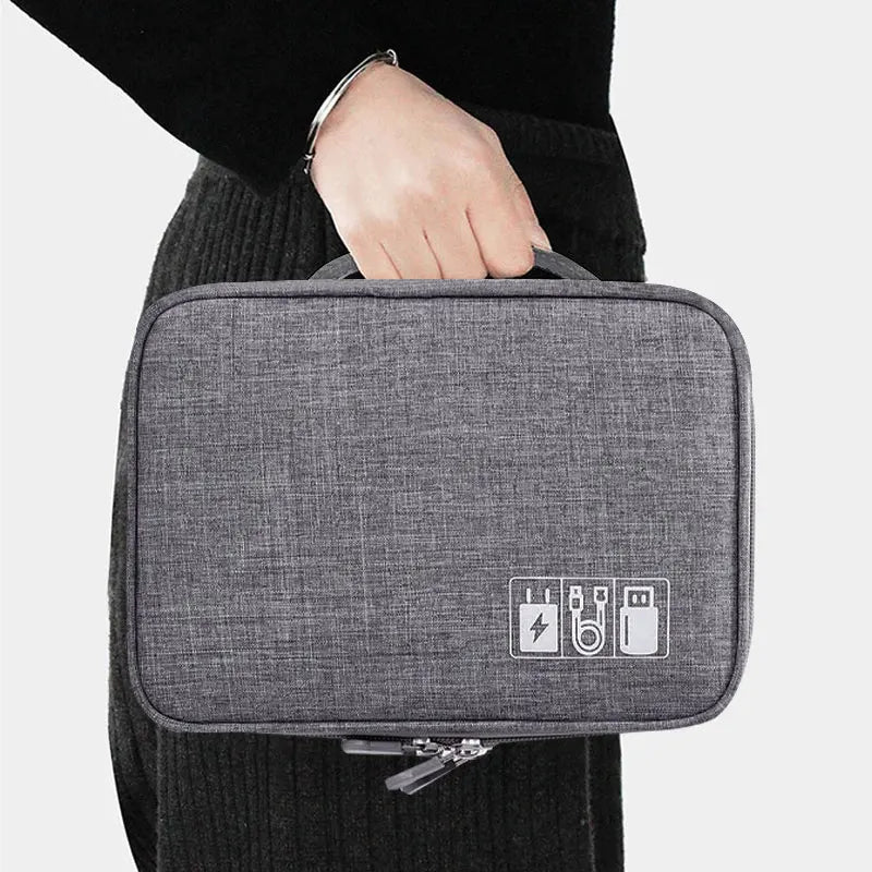 A person holding a gray tech organizer bag with icons for charging and USB cables on the front, against a plain background.