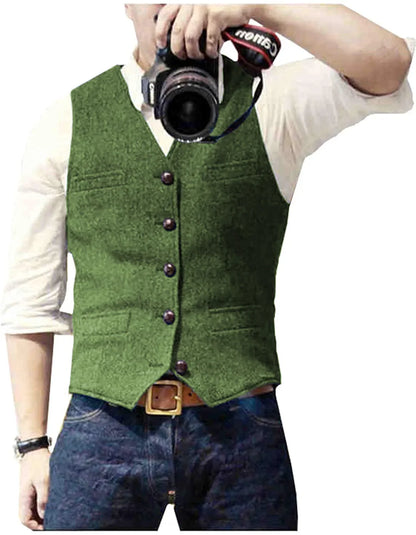 Man in a green vest with buttons and pockets, holding a camera, dressed in a white shirt and blue jeans.