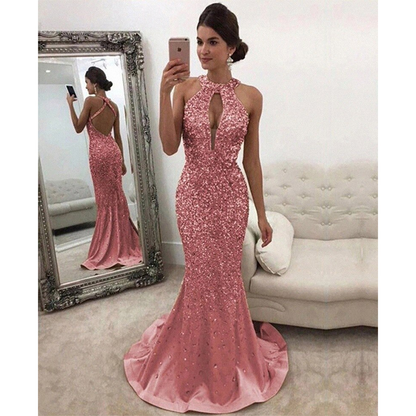 A woman wearing pink gown. The dress has a halter neckline and open back, with a fitted bodice and flared skirt.