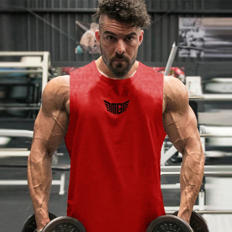 A muscular individual in a red sleeveless shirt lifts dumbbells in a gym, showcasing strength and dedication to fitness.