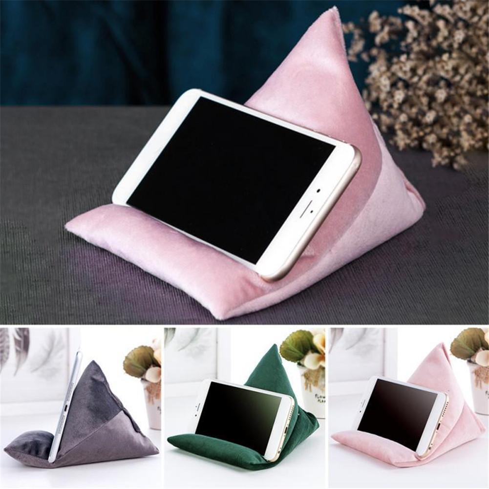 A smartphone rests on a soft, triangular stand in pink, gray, and green colors, providing a stylish and functional display.
