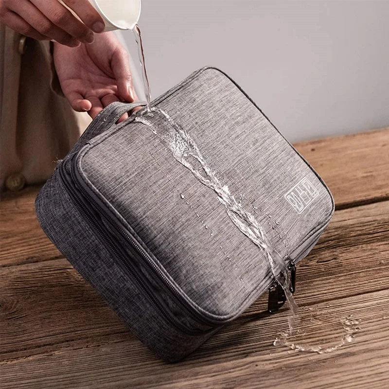 A person pours water onto a gray, water-resistant bag, demonstrating its ability to repel liquids.
